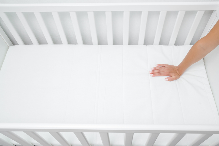 Baby's crib with just a sheet on the mattress, ready for baby to come